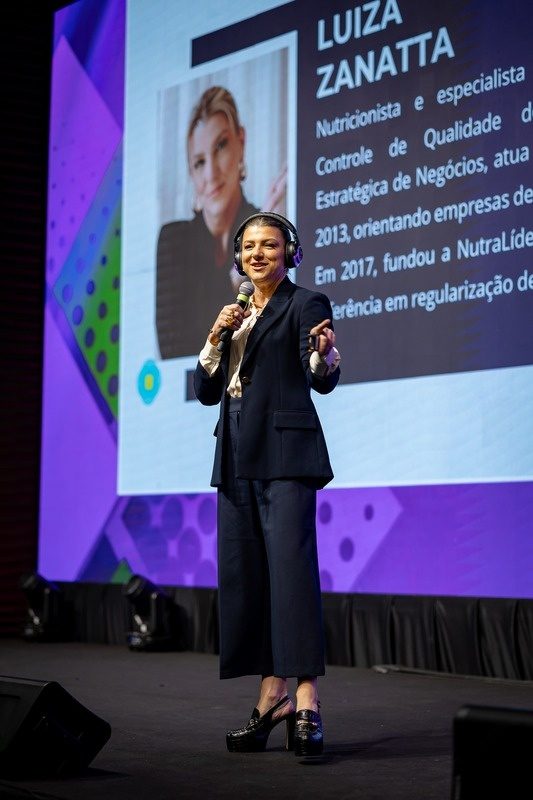 Luiza Zanatta apresentando um treinamento em um palco